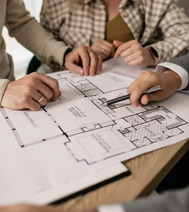 People discuss architectural plans in a real estate planning session, highlighting teamwork.